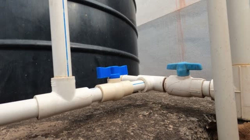 فیتینگ نصب شده روی مخزن آب پلاستیکی به همراه اتصالات مانند سه راهی، لوله ها و فلکه