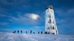 مخزن آب هوایی که در سرما و یخبندان یخ زده و چند فرد در حال تلاش برای یخ زدایی آن هستند