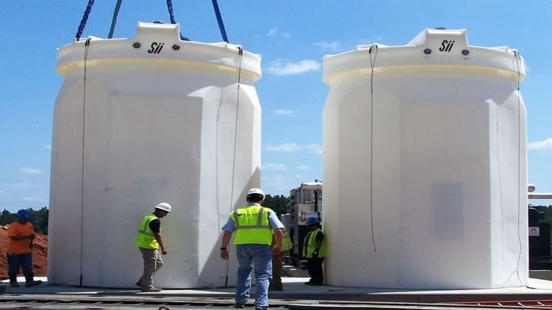 دو مخزن آب پلی اتیلن(پلاستیکی) با ابعاد بزرگ در حال انتقال به محل نصب توسط جرثقیل