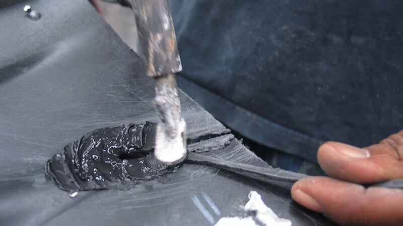 یک فرد متخصص در حال تعمیر و ترمیم یک مخزن آب پلاستیکی با اتفاده از چکش می‌باشد