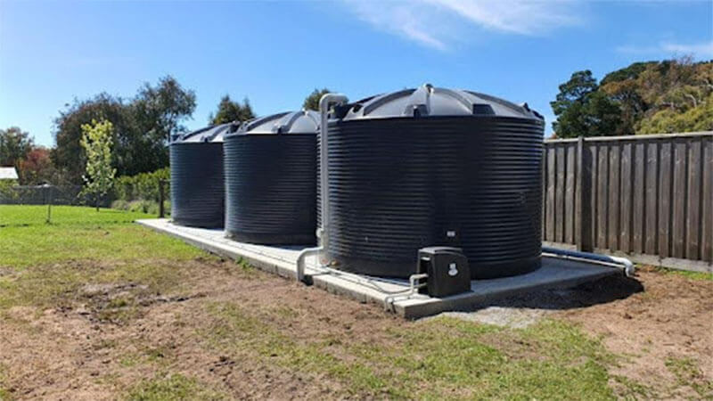 سه مخزن آب پلاستیکی با رنگ مشکی در یک زمین کشاورزی نصب شده اند